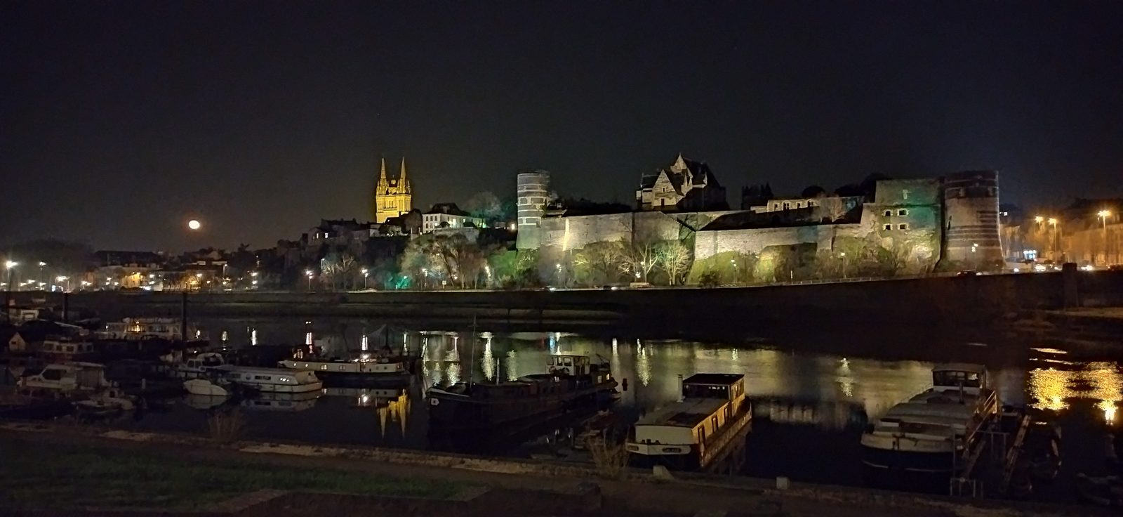 Le château d'Angers et la cathédrale illuminés de nuit, au bord de la Maine